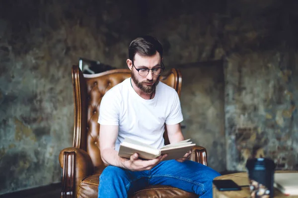 Serious Bearded Man Eyeglasses Casual Outfit Sitting Leather Armchair Reading — Stock Photo, Image