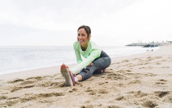 Retrato Jogger Feminino Esportivo Olhando Para Câmera Enquanto Aquece Músculos — Fotografia de Stock