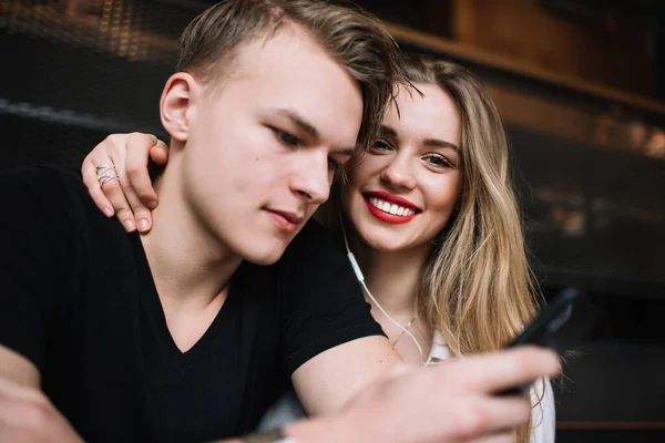 一对快乐的年轻夫妇在一起开会的时候一起在咖啡馆里坐着浏览智能手机 在周末放松的时候笑着 — 图库照片