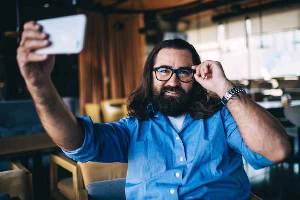 Hombre Barbudo Positivo Gafas Sonriendo Mirando Cámara Mientras Está Sentado — Foto de Stock