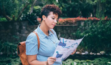 Popüler yerleri keşfetmek için gündüz gezileri için kağıt harita okuyan çekici kadın turistlerin yan görüntüsü, sırt çantalı İspanyol kadının yaz tatilleri var