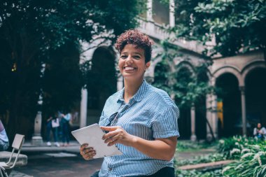 Şehirde boş zamanlarında 4G kablosuz internet bağlantısı kullanan samimi kadın portresi, dijital tabletle kameraya gülümseyen müreffeh bin yıllık blog yazarı