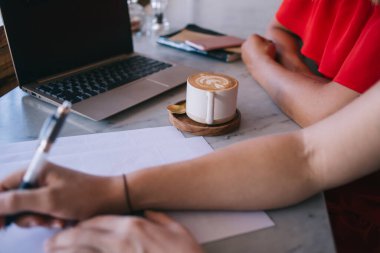 Gündelik giysiler içinde isimsiz iş arkadaşları masada oturup laptopta uzak bir proje üzerinde çalışırken kafede vakit geçirirler.