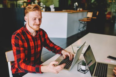 Bluetooth uygulaması yüklemek ve medya dosyalarını çalışan bilgisayara paylaşmak için dijital akıllı telefonu kullanan başarılı erkek bilişim uzmanı, uzaktaki iş arkadaşlarıyla sohbet etmek için telefon eden beyaz adam