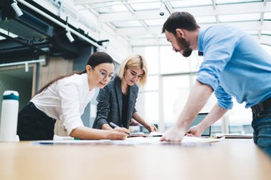 Kağıtlarla çalışan ve büyük pencereli büyük rahat ofiste parlak kalemli çizimler ve şemalar çizen bir grup meslektaşım var.