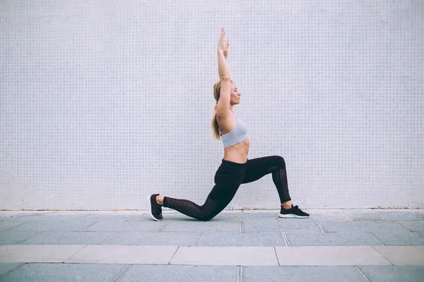 在空荡荡的街道上练习瑜伽时 冷静的女士伸出双臂做阿萨那和做隆起动作的侧视图 — 图库照片