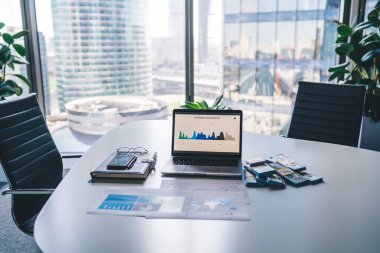 Elektronik netbook teknolojisi, bilgisayar ekranında ticari bilgiler, dokümanlar ve para dolu ders kitabı, masa başında duruyor, web panelinde grafik analitik çizelgeleri olan modern bilgisayar.