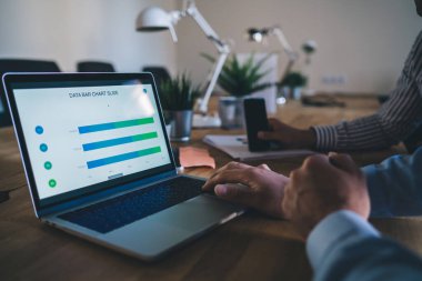 Modern dizüstü bilgisayar seçici odak noktası gelir istatistiklerinin finansal web sitesi, veri bilgilerini kontrol eden erkek profesyonellerin kırpılmış görüntüsü çevrimiçi bilgi raporları üzerinde beyin fırtınası yaparken