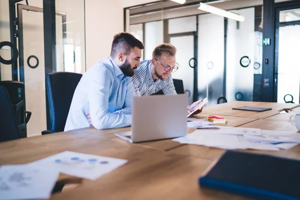 Caucasian male colleagues 30s watching online media content analyzing online information cooperating together, skilled men entrepreneurs planning strategy using technology for digital marketing