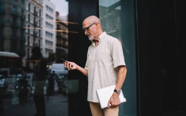 Son sınıf öğrencileri, günlük kıyafetlerini giyip şehir sokağında, tabletli ve cep telefonlu bir şekilde dikiliyorlar.
