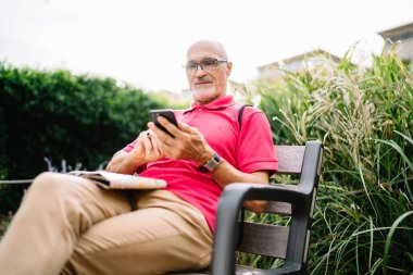 Gözlüklü beyaz adam ağ sohbetleri sırasında akıllı telefon e-postası aldı. Yetişkin bir erkek blogcu cep telefonu teknolojisiyle video izlerken yayın bilgisini okuyor.