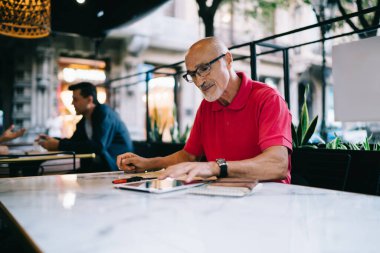 Modern dokunmatik sayfaya medya uygulaması yükleyen erkek kullanıcı boş zamanlarında masada oturuyor ve mesajlaşıyor, klasik göz giyimi konusunda Kafkas üst düzey dijital tableti güncellemek için bildirimi kontrol ediyor