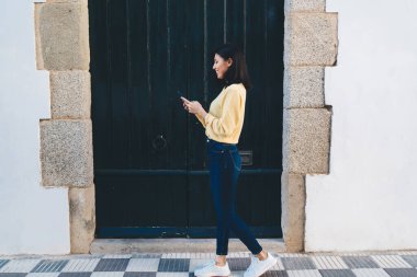 Mutlu Asyalı bir kızın şehir turundan zevk almasının yan görüntüsü modern cep telefonu aygıtlarını sohbet etmek ve mesajlaşmak için kullanması, gezintiler sırasında neşeli bayan turistlerin GPS 'leri takip etmesi.