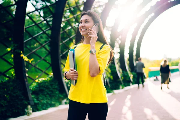 スマートフォンでローミング接続を使用して話を路上で本と散歩カジュアルウェアで幸せなアジアの女性 晴れた日に携帯電話で肯定的な会話をして陽気な女性のヒップスター — ストック写真