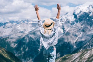 Güneşli bir günde Lago di Braies 'e yapılan gezide, sıradan kıyafetli, kollarını kaldıran ve dağlara hayran olan kimliği belirsiz bir kadının arka görüntüsü.