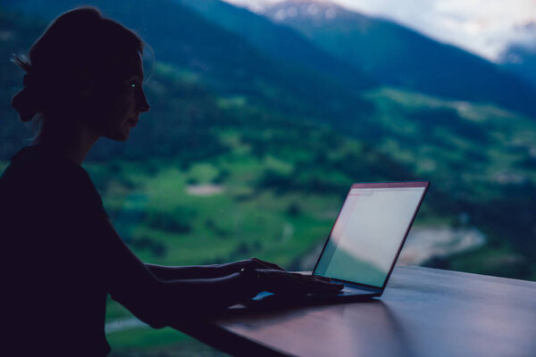 Силуэт тысячелетней женщины проверки настройки на ноутбуке устройства, сидя за столом и используя Wi-Fi веб-соединение для онлайн-связи, женщина цифровой кочевник делает внештатную работу во время отпуска