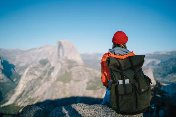 带背包的无名徒步旅行者坐在山顶上 一边环顾约塞米蒂国家公园 一边回头看 — 图库照片