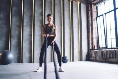 Aktif giyimde kararlı bir kadın kasları için ip kullanıyor. Spor salonunda zayıflamak için zaman harcıyor. Beyaz tenli güzel kadınlar kardiyo egzersizi yapıyor.