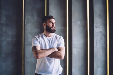 Sıradan giyinmiş yakışıklı beyaz bir erkek spor salonunda dikilip tatil hayalleri kuruyor. Beyaz tişörtlü, fotokopi alanı olan genç bir sporcu.