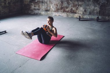 Aktif giyinmiş, kulaklık takmış, gülümseyen beyaz kadın antrenman ve sağlıklı yaşam tarzından zevk alan pozitif kadın karın kasları için egzersiz yapan ve müzik dinlemek için kulaklık kullanan kadın.