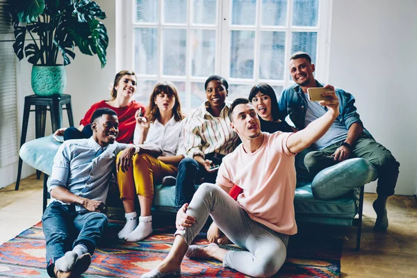 Çeşitli milenyum insanları rahat koltukta rahat rahat oturup fotoğraf çekmek için akıllı telefon kamerasıyla zaman geçiriyorlar, genç arkadaşlar medya içeriğini web sitesine paylaşmak için selfie çekiyorlar.