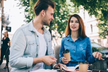İçerideki kadın ve adam işten sonra kahve içip kahve içerken yaz mevsiminde güneşli bir kafede oturuyorlar.