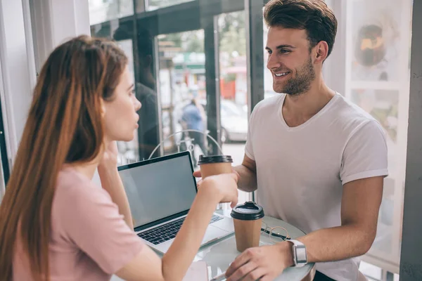 Sorrindo Jovens Colegas Trabalho Roupas Casuais Mesa Com Laptop Segurando — Fotografia de Stock