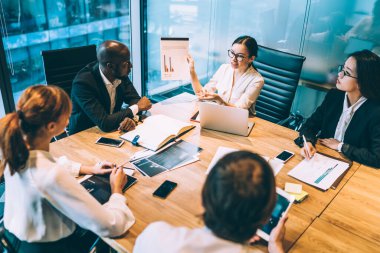 Ortaklık konferansı sırasında finansal istatistikleri tartışan profesyonel tüccarlar, birlikte brifing sırasında verimli iş stratejileri hakkında konuşan deneyimli uzmanlar, grafik çizelgelerini analiz eden