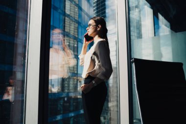 Resmi olarak giyinmiş kadın sekreter, şirket ofisinde çalışırken detayları açıklamak için şirket patronunu arıyor, Kafkas gururlu CEO, uluslararası ortakla iletişim kurmak için cep telefonu uygulamasını kullanıyor.