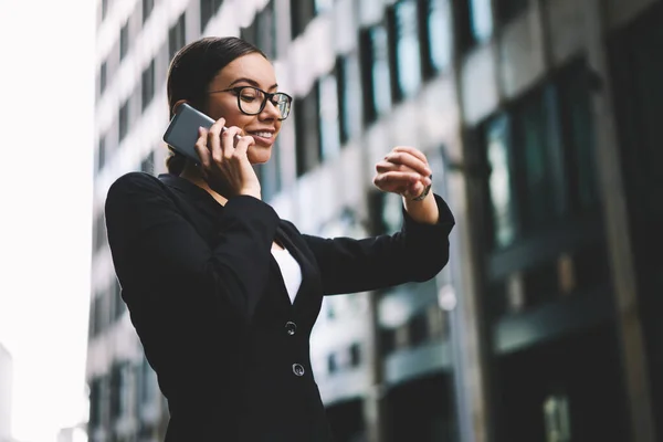 Allvarlig Kvinna Glasögon Och Kontorskläder Talar Smartphone Och Kontrollerar Tiden — Stockfoto