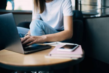 Çalışan bir kız öğrencinin teknoloji ve ders kitaplarıyla çevrimiçi araştırma ve öğrenim yaparken çekilmiş görüntüsü, 20li yaşlarda beyaz bir blogcu bilgisayarında multimedya paylaşımı için yazı yazıyor.