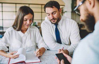 Genç erkek ve kadın mimarlardan oluşan bir grup mühendislik projesiyle ilgili fikirleri masaya yakın planlarla tartışıyor, başarılı profesyoneller çizimlerle birlikte çalışma sürecine sahip.