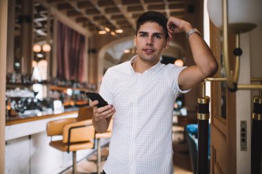 Sosyal medyada mesajlaşırken ve molada kameraya bakarken akıllı telefonlu neşeli erkek.