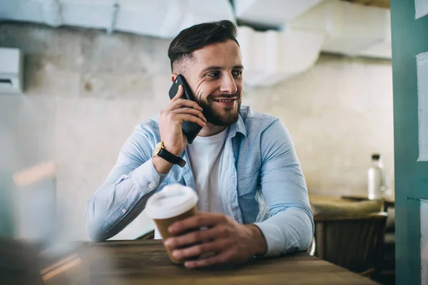 Homem Barbudo Positivo Camisa Azul Casual Falando Smartphone Enquanto Sentado — Fotografia de Stock