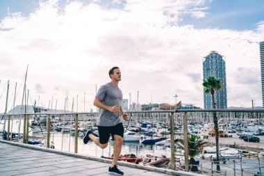 Eşofmanlı genç hippi sabah dışarıda koşan kardiyo esnekliği ve dayanıklılığı idman yapıyor. Beyaz erkek koşucu antrenmana başlıyor. Vücut şeklini ve fiziksel gücünü koruyor.