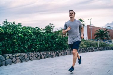 Yakışıklı kararlı aktif erkek koşucu kardiyo eğitimi sırasında enerji ve gücün tadını çıkarıyor sağlıklı yaşam tarzını koruyor, 20 'li yaşlarda güçlü kaslı güçlü vücudu olan beyaz adam şehirde antrenman yapıyor.