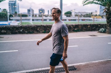 Neşeli beyaz hippi adam sokakta koştuktan sonra dinleniyor. Kardiyo hedeflerine ulaşıyor. Mükemmel vücut şeklini koruyor.