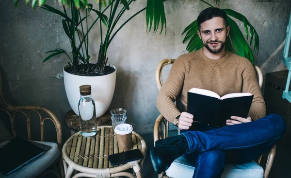 Homem Barbudo Sentado Poltrona Lendo Livro Interessante Cafetaria Moderna Vestindo — Fotografia de Stock