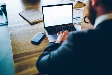 Kesilmiş erkek girişimci ofis internetine bağlı online yatırımı analiz etmek için maket dizüstü bilgisayar kullanıyor, kopyalama alanı olan boş bir ağda deneyimli iş adamı arama bilgileri