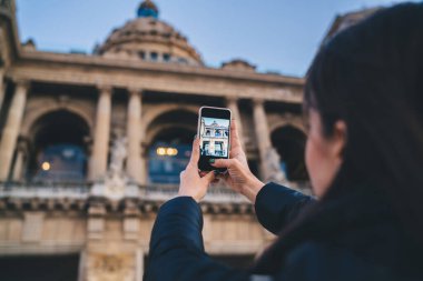 Anonim esmerin arka planda kalan görüntüleri, eski otantik tarihi katedralin akıllı telefonuna akşamları sütunları ve kubbesi olan fotoğraflar çekiyor.