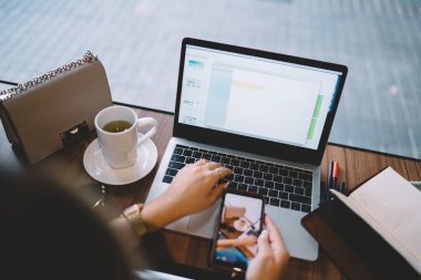 Modern dizüstü bilgisayarda, kafenin içinde serbest çalışan bir kadının, internet sayfasında paylaşım için modern cihazlar kullanan bir kadının elinin klavye üzerindeki resminden kesilmiş görüntüsü.
