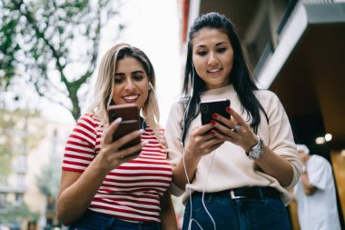 Modern akıllı telefonlarda bluetooth bağlantısıyla medya dosyalarını paylaşan, ses podcast 'ini dinleyen, elektronik kulaklıklı hipster kızları çevrimiçi hareketlilik mesajlarının keyfini çıkaran mutlu bin yıllık kullanıcılar.