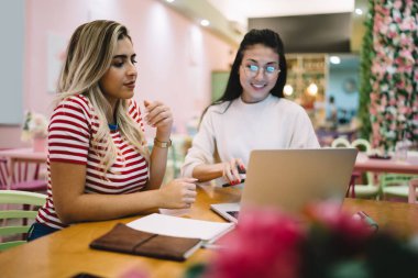 Çevrimiçi kurslarda eğitim ağı kuran serbest gençler, modern dizüstü bilgisayarda web tarayıcı için cafe wifi bağlantısı kullanıyorlar ve uygulama kurarken ağ haberleri okuyan yetenekli kadınlar.