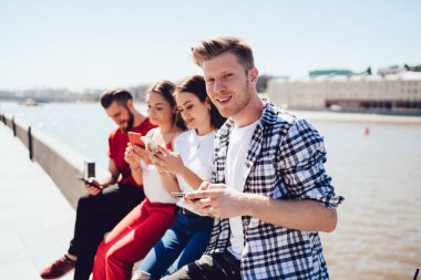 Yakışıklı adamın portresi, bluetooth 'a bağlı senkronize akıllı telefon cihazları ile online oyunlar oynayan beyaz tenli hippi çocuklarla buluşmaktan keyif alıyor.