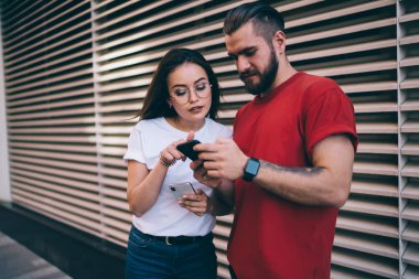 Kafkasyalı erkek ve kadın blogcular, kentteki tarih eğlencesi sırasında web yayınını tartışıyorlar. Modern akıllı telefon teknolojisinde 4G kablosuz internet sitesine bağlanan milenyum hipster erkekler.