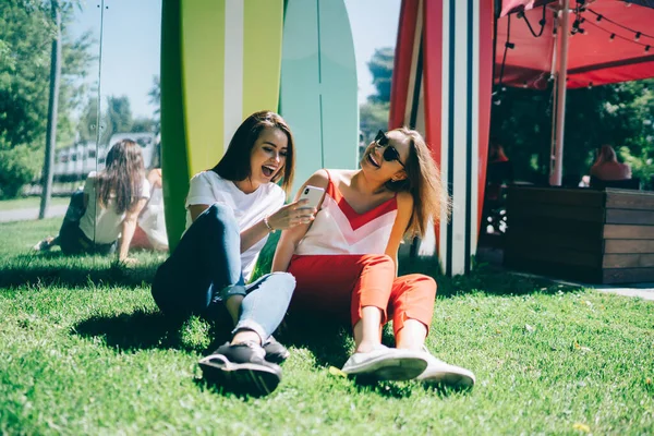 Happy Caucasian hipster girls watching funny web vlog and smiling using 4g wireless connection during leisure time,female bloggers discussing network publication and laughing satisfied with friendship