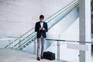 Yakışıklı, refah içinde yaşayan Hindu işadamı seyahat için çantanın yanında duran cep telefonunu kullanıyor. Akıllı telefondan akıllı Ceo haberleri okuyor.