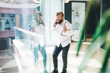 Başarılı erkek pazarlamacı akıllı günlük kıyafetlerle cep telefonu aygıtını kullanarak teknoloji uygulaması üzerinden dostça bir telefon görüşmesi yapıyor. Zengin adam 20 yaşında ve hareketlilik sohbetinin keyfini çıkarıyor.