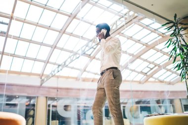 Beyaz giyimli Afro-Amerikan erkek ofis molasında online cep telefonu konuşması yapıyor. Başarılı adam cep telefonu teknolojisiyle kablosuz internet bağlantısı kullanarak arıyor.