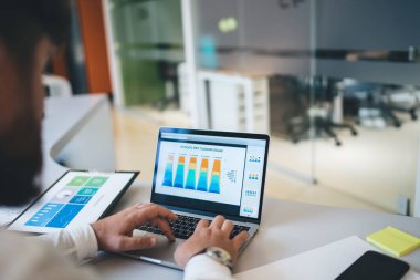 İş gelirleri hakkında çevrimiçi finans raporu oluşturan dizüstü bilgisayarda yazı yazan bir erkeğin görüntüsü, iş yerindeki istatistik gelirleri için araştırma ve grafik şemaları yapan bir adamın elleri